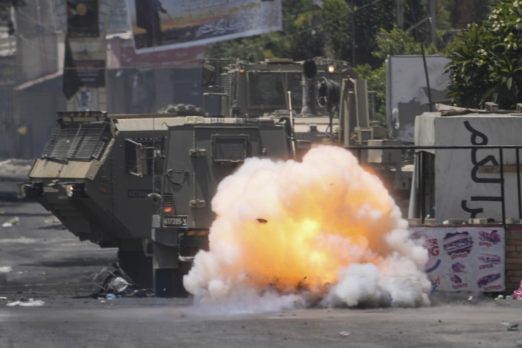 A bomb thrown by a Palestinian explodes next to an Israeli army vehicle Jenin on Tuesday. Photo: AP