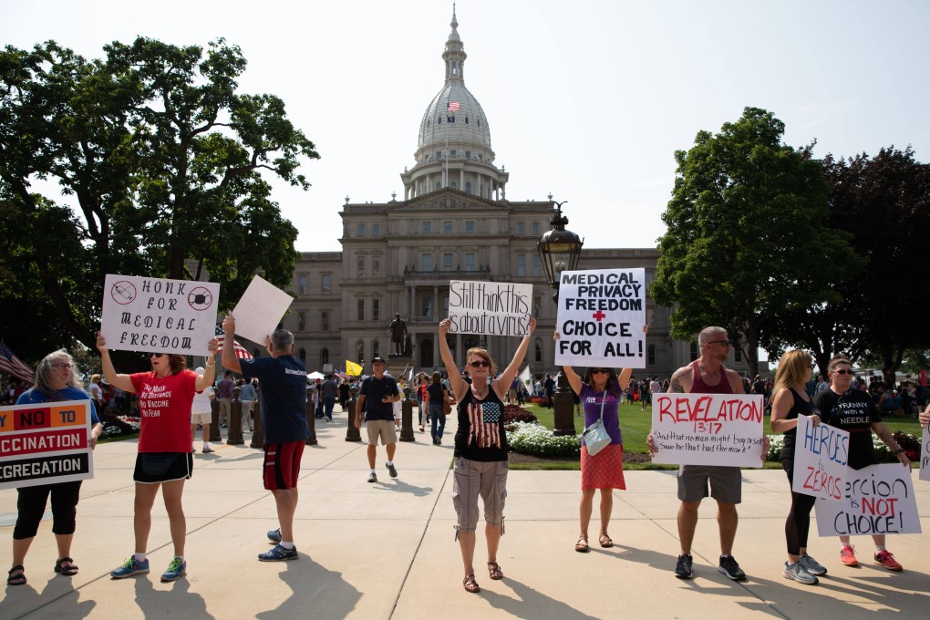 Demonstrators hold signs as they protest against mandated vaccines outside the Michigan State Capitol on August 6, 2021. Photo: Getty Images/AFP
