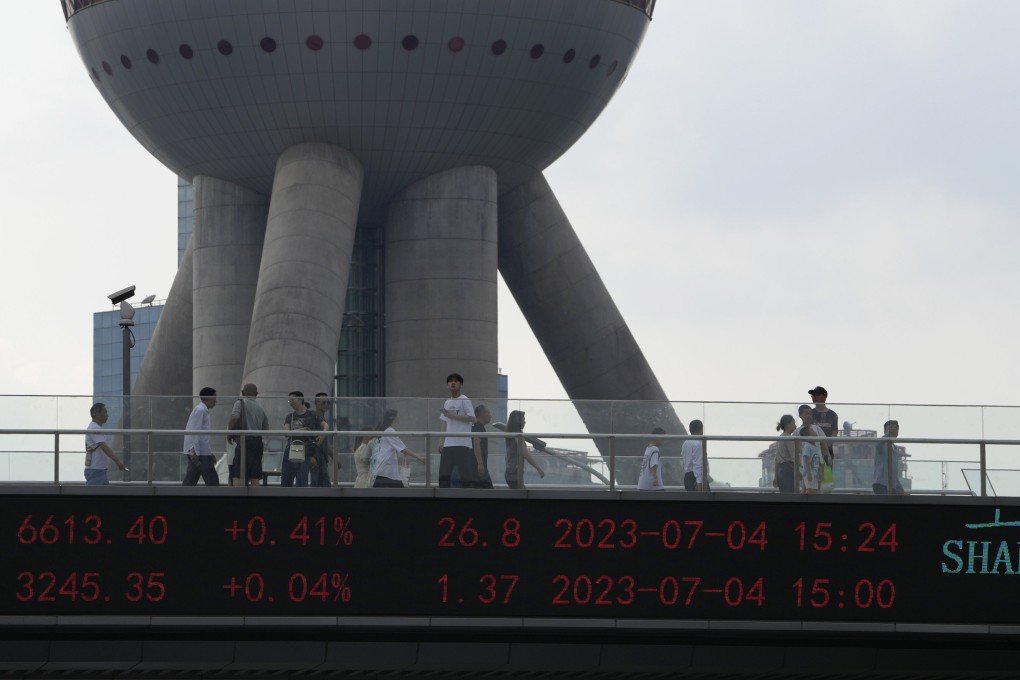 Residents pass the Oriental Pearl Tower near displays showing Chinese stock market indices in Shanghai on Tuesday. China’s sluggish recovery from the ravages of the Covid-19 pandemic has some observers worried its economy could be headed the same direction as Japan’s after the bursting of its asset bubble in the early 1990s. Photo: AP