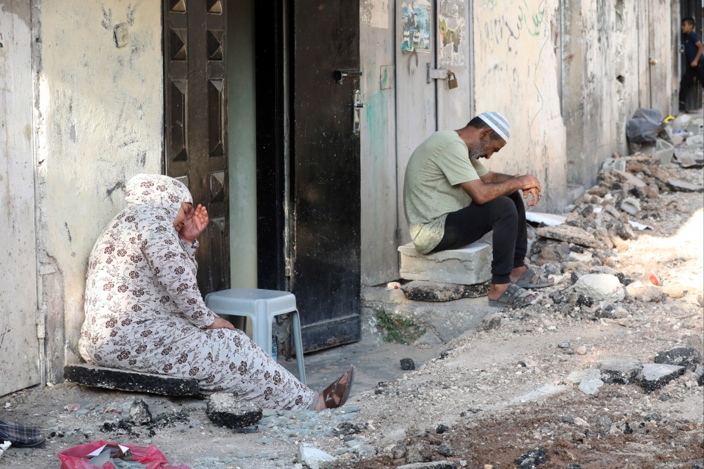 Palestinians sit outside their damaged house at Jenin refugee camp after an Israeli army raid in the West Bank city of Jenin on Friday. Photo: EPA-EFE