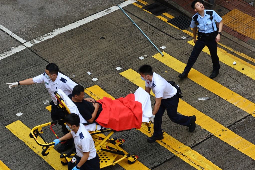 Paramedics wheel an injured driver to safety after he was hit by falling concrete chunks from a building. Photo: Dickson Lee
