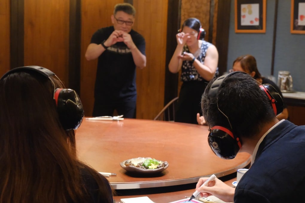 Keith Lee Kam-wah, who has been deaf since he was young, assists the SCMP’s Charmaine Mok with acting out the name of a dim sum dish at a silent yum cha session. Photo: Eaton HK