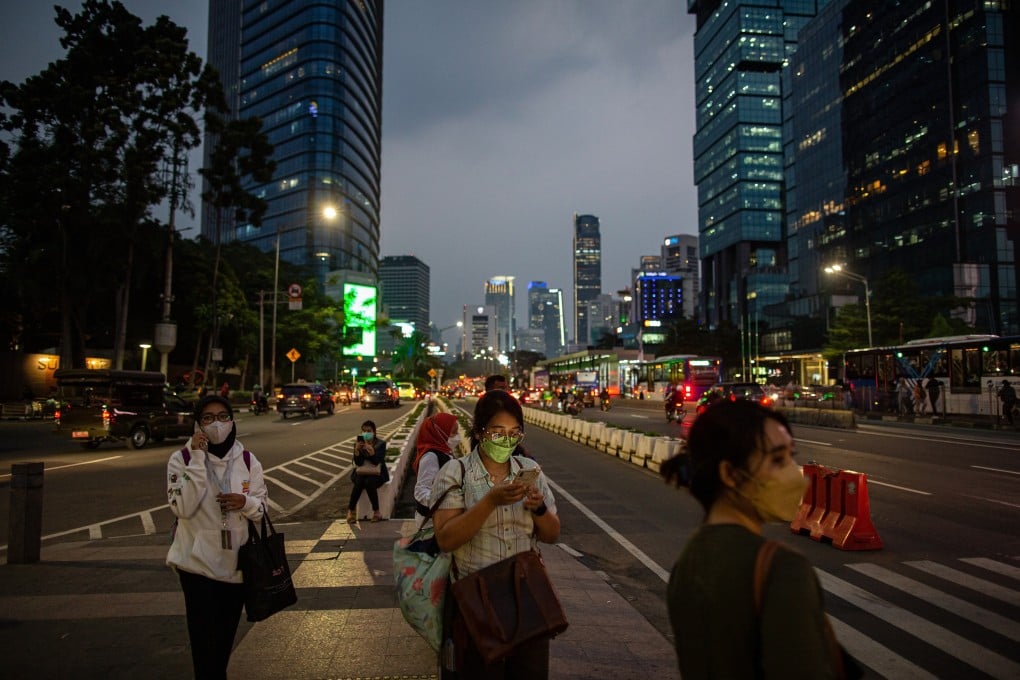 People use their smartphones while walking through Jakarta’s central business district on June 30, 2022. The digital and fintech revolution in Indonesia has allowed more people access to finance but also led to a rise in reckless spending and accumulated debt through online lending. Photo: Getty Images