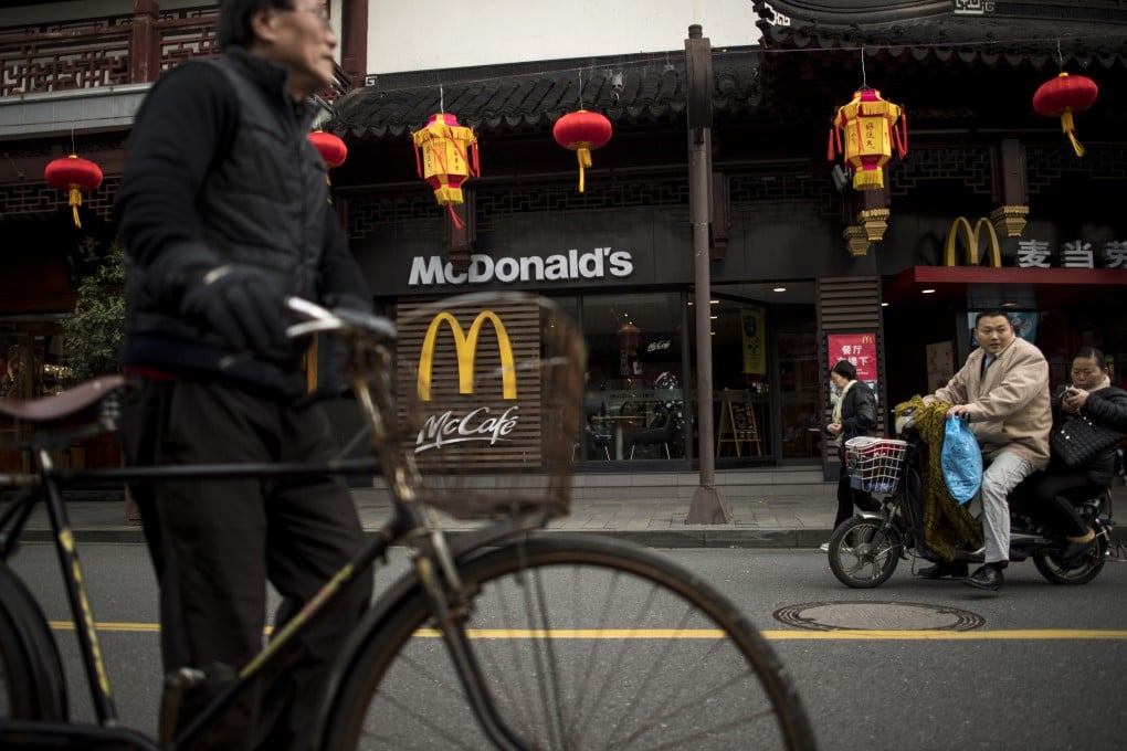 A man pushes his bicycle in front of a McDonald’s fast food restaurant in Shanghai. Photo:AFP