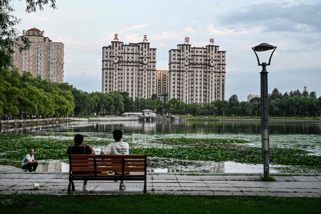 People relax by a lake near residential buildings in Hegang city in northeastern China’s Heilongjiang province. Photo: AFP