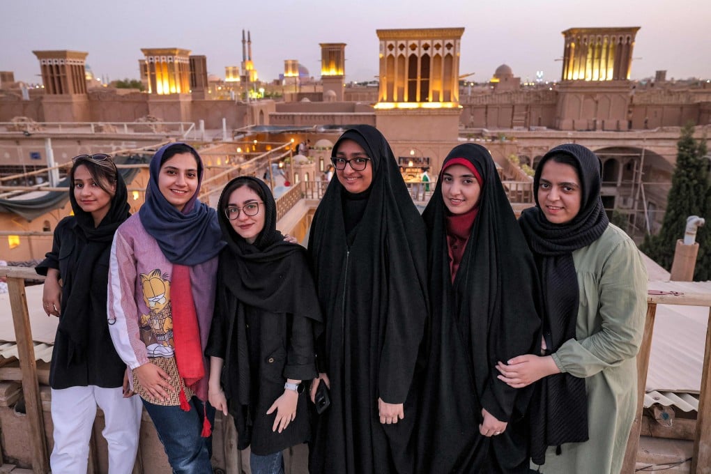 Women pose for a group photo with wind catchers (“badir” in Persian) dotting the skyline behind, on a rooftop in Iran’s central city of Yazd in July, 2023. Iran is making a push to attract more visitors to boost its sanctions-hit economy. Photo: AFP