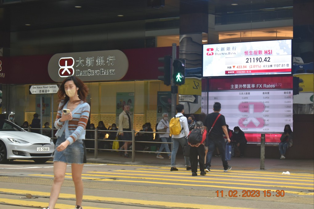 People crossing a busy street in Central, Hong Kong with an electronic board showing Hang Seng Index in February 2023. Photo: Li Jiaxing