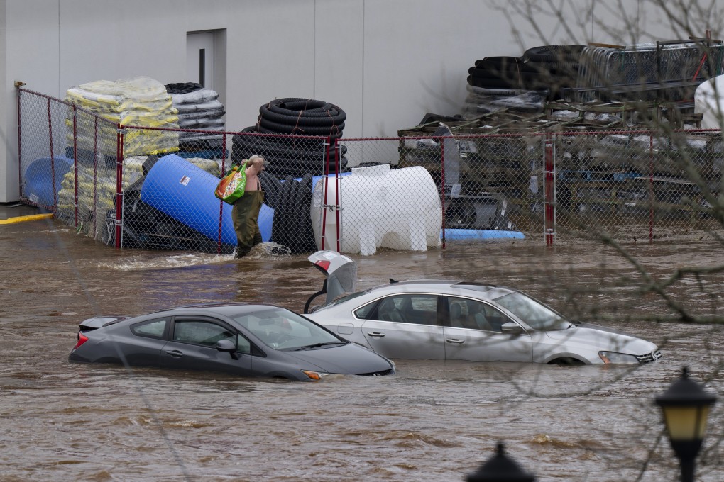 A man wearing chest waders walks past cars abandoned in floodwaters in a shopping centre car park in Halifax, Nova Scotia, Canada on Saturday. Photo: The Canadian Press via AP