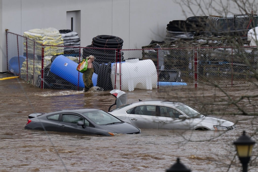 A man wearing chest waders walks past cars abandoned in floodwaters in a shopping centre car park in Halifax, Nova Scotia, Canada on Saturday. Photo: The Canadian Press via AP