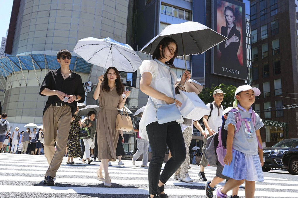 People protect themselves from the scorching sun with parasols and headgear in Tokyo’s Ginza shopping district earlier this month. Photo: Kyodo