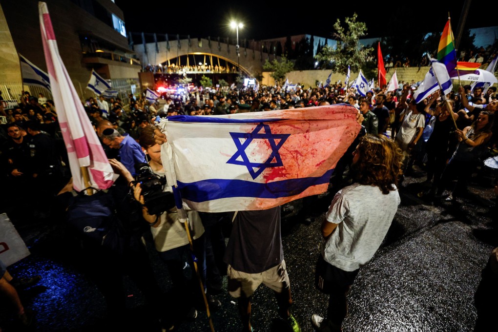 A protester holds an Israeli flag, stained with what he claims is blood, during a demonstration near the Knesset, Israel’s parliament, in Jerusalem on Monday. Photo: Reuters