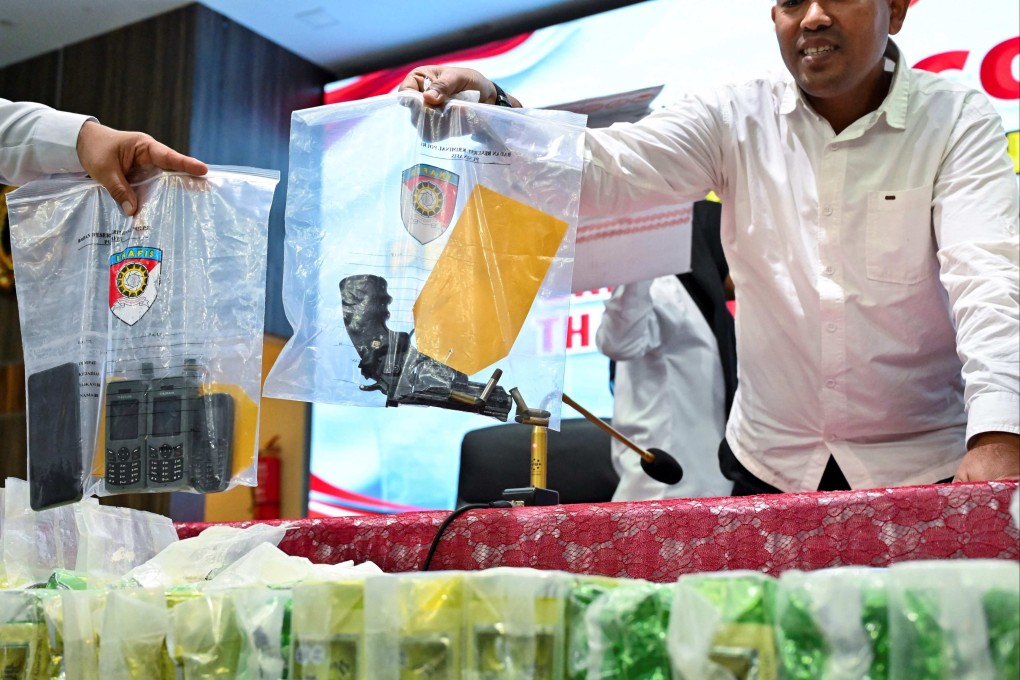 Police officers hold evidence bags containing a pistol and satellite phones during a press conference. Indonesian police are investigating an illegal trade in human organs involving a police and an immigration officers who were accused of helping traffickers send 122 Indonesians to a hospital in Cambodia to sell their kidneys, police said. Photo: AFP