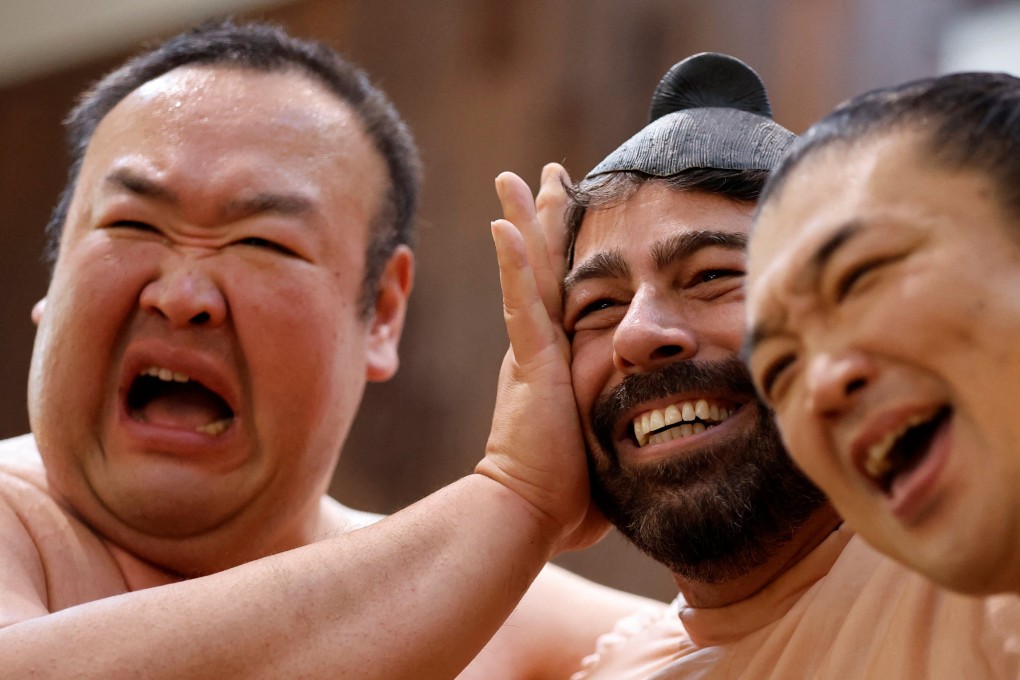 Japanese former sumo wrestlers Kotoohtori (left) and Towanoyama (right) pose for a photograph with a US national in Tokyo last month. Foreign residents now account for 4.2 per cent of the Japanese capital’s population. Photo: Reuters