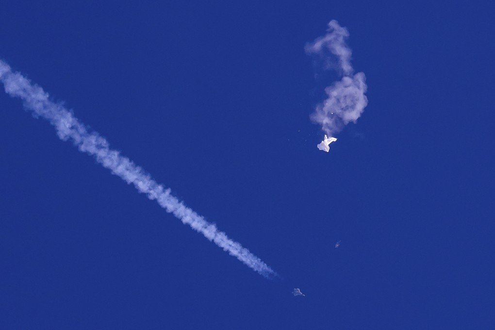 A fighter jet flies past the remnants of a large balloon falling into the Atlantic Ocean after it was shot down just off the coast of South Carolina on February 4, 2023. Photo: AP