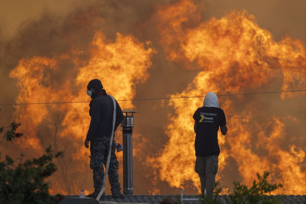 Residents stand on their roofs on July 25 in front of huge flames in the Greek village of Gennadi during forest fires on the island of Rhodes. Several regions across Greece are still on high alert. Photo: dpa