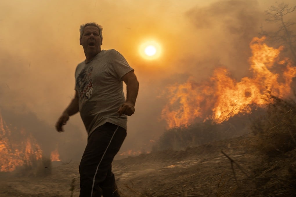 A local reacts as the flames burn trees in Gennadi village on the Greek island of Rhodes on Tuesday. Photo: AP