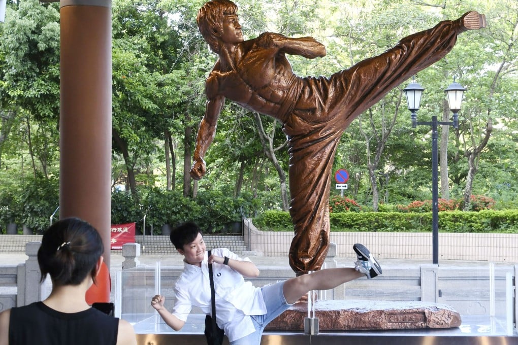 A visitor imitates Bruce Lee in front of a statue of the kung fu legend at the Hong Kong Heritage Museum in Hong Kong. Photo: Kyodo