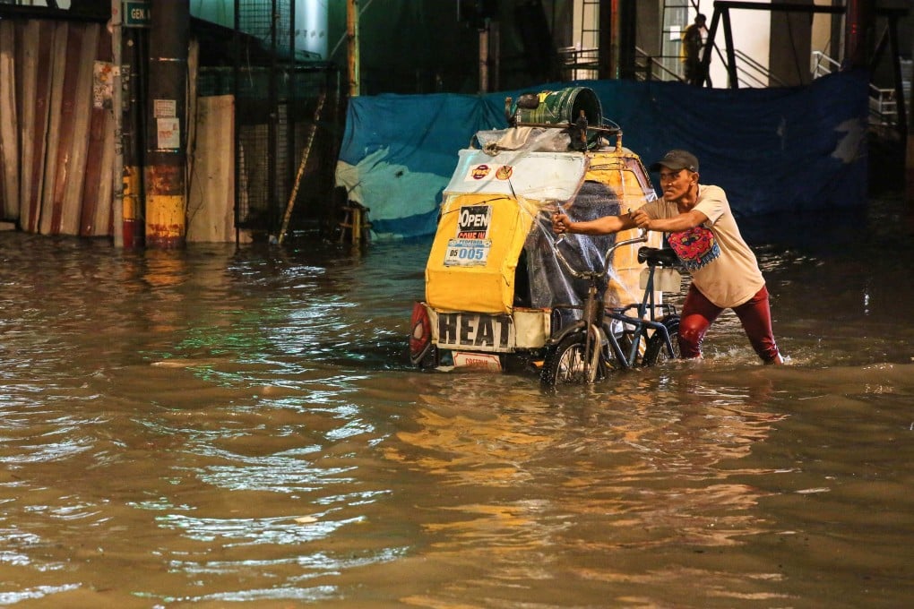 A man pushes his pedicab through a flooded street of Manila as Khanun intensifies the southwest monsoon rain on Saturday. Photo: AFP