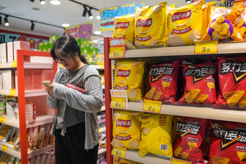A woman uses her cellphone in a food store at a mall in Beijing in July. Photo: EPA-EFE