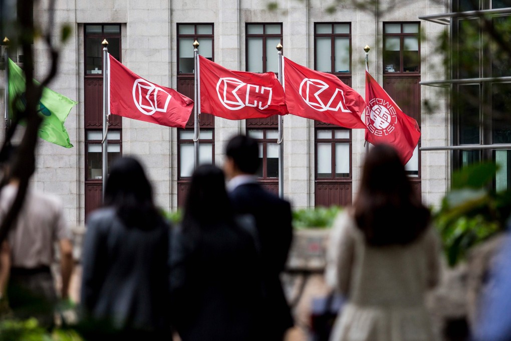 People walk near flags of CK Hutchinson Holdings outside the company’s headquarters in Hong Kong on March 21, 2019. Photo: AFP