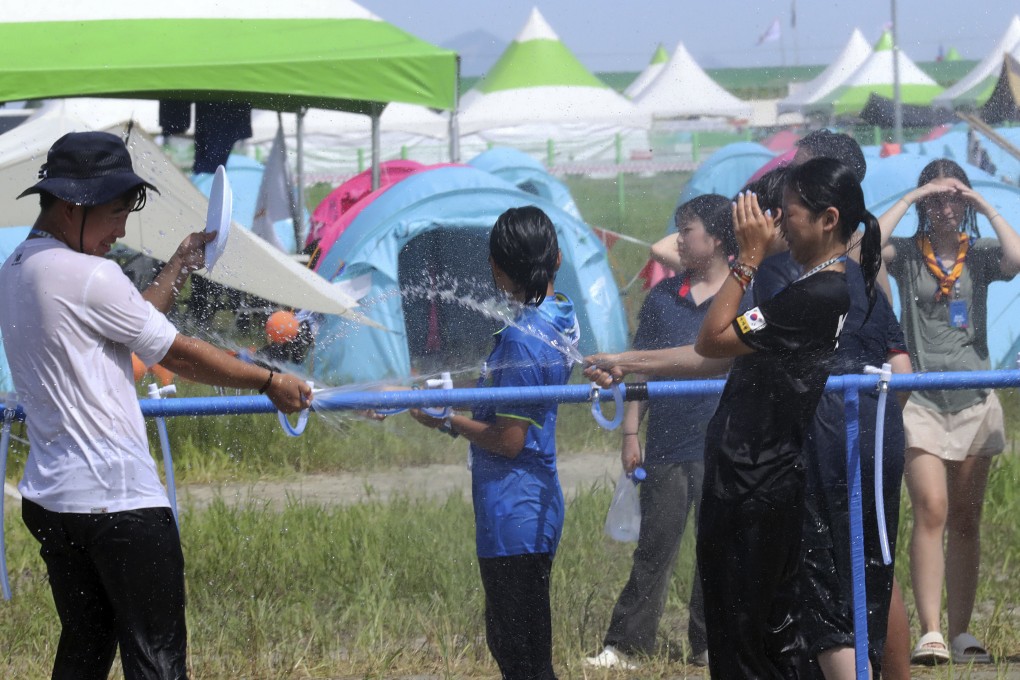 Attendees of the World Scout Jamboree cool off with water at a scout camping site in Buan, South Korea, on Friday. Photo: Yonhap via AP