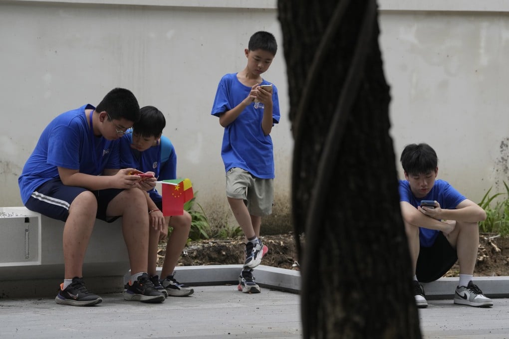 Children look at their smartphones on a street in Beijing on Thursday. Photo: AP Photo