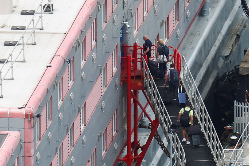 People carrying bags board the Bibby Stockholm barge at Portland Port, near Poole in Britain, on Monday. Photo: Reuters