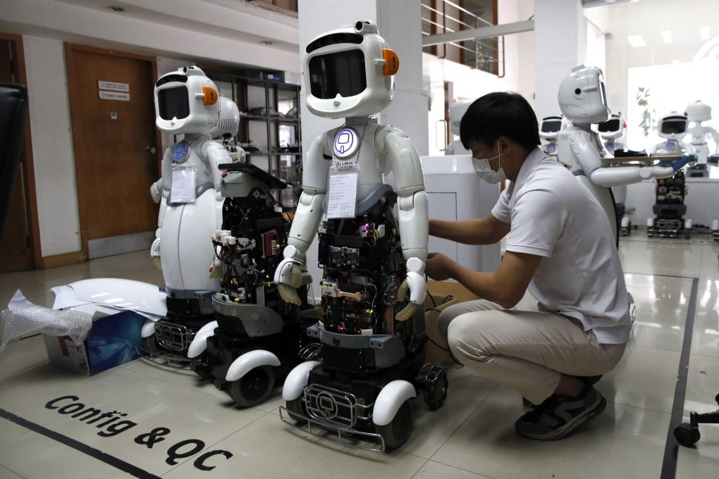 A technician sets up Dinsaw robots designed for healthcare and service businesses at CT Asia Robotics in Bangkok on July 24. The Dinsaw Mini 3 combines three artificial intelligence which can communicate with people, such as by offering medication reminders, and alert health emergencies to carers in case of unusual activity. Photo: EPA-EFE