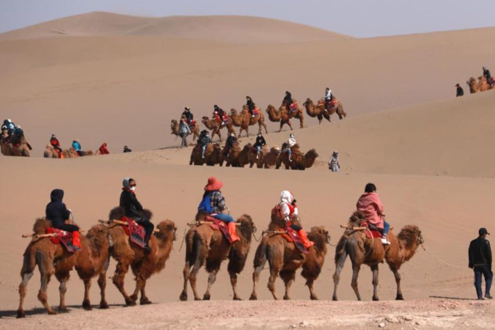 Tourists ride camels at the Mingsha Mountain and Crescent Moon Spring in Dunhuang City. Photo: Xinhua
