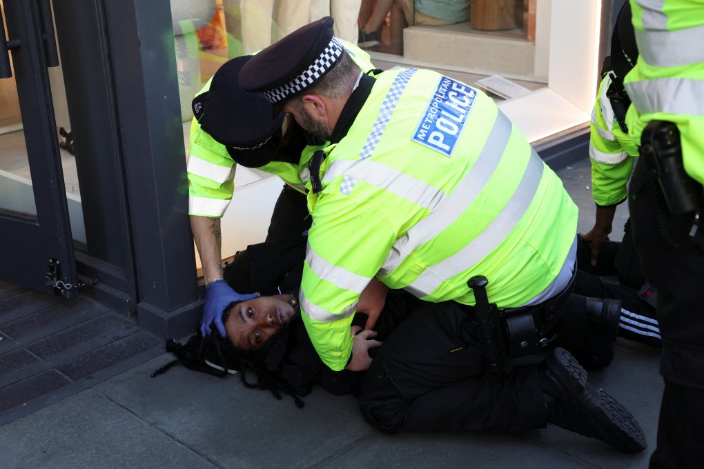 Police officers detain a person as disruptors target shops during a shoplifting spree flash mob on Oxford Street in London on Wednesday. Photo: Reuters