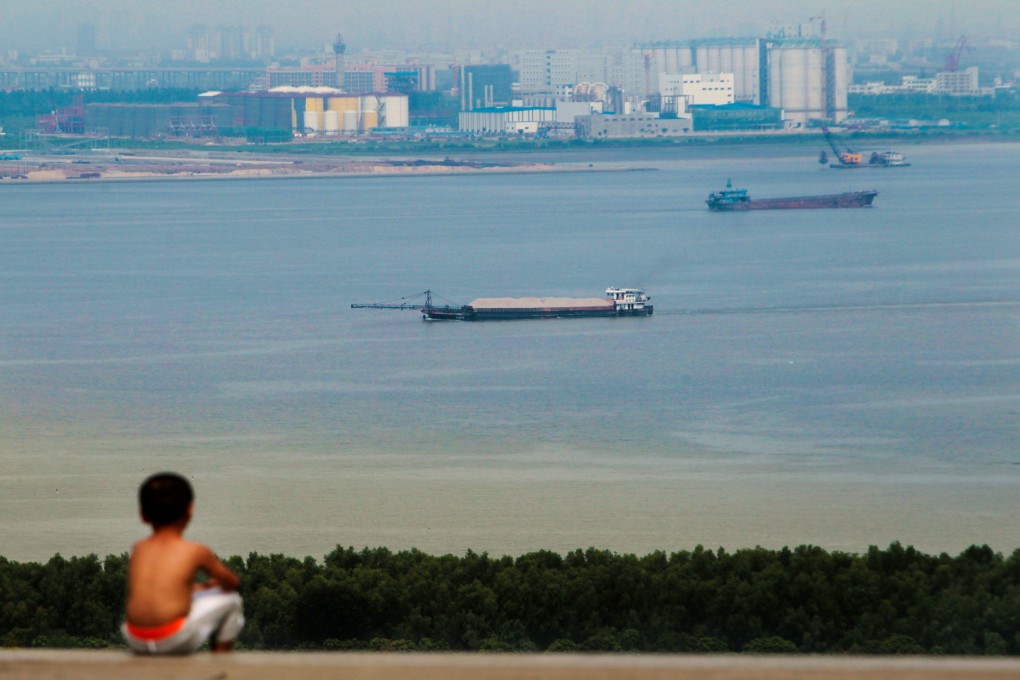 A boy looks at cargo ships passing along the Pearl River in Guangzhou in China’s Guangdong province in August  2014. Chinese shipping giant Cosco recently launched its first fully electric vessel. Photo: Reuters