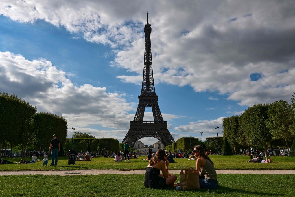 Tourists and Parisians sit in the Champ de Mars in front of the Eiffel Tower in Paris. Photo: AFP