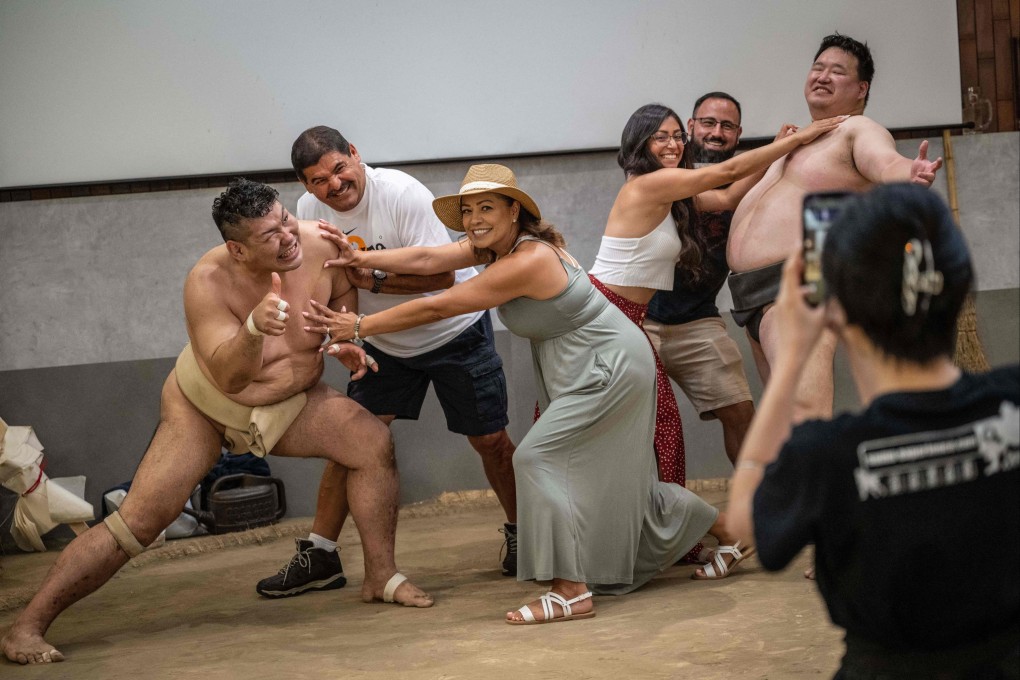 Foreign tourists posing for photographs with former sumo wrestlers at a restaurant in Tokyo in July. Photo: AFP