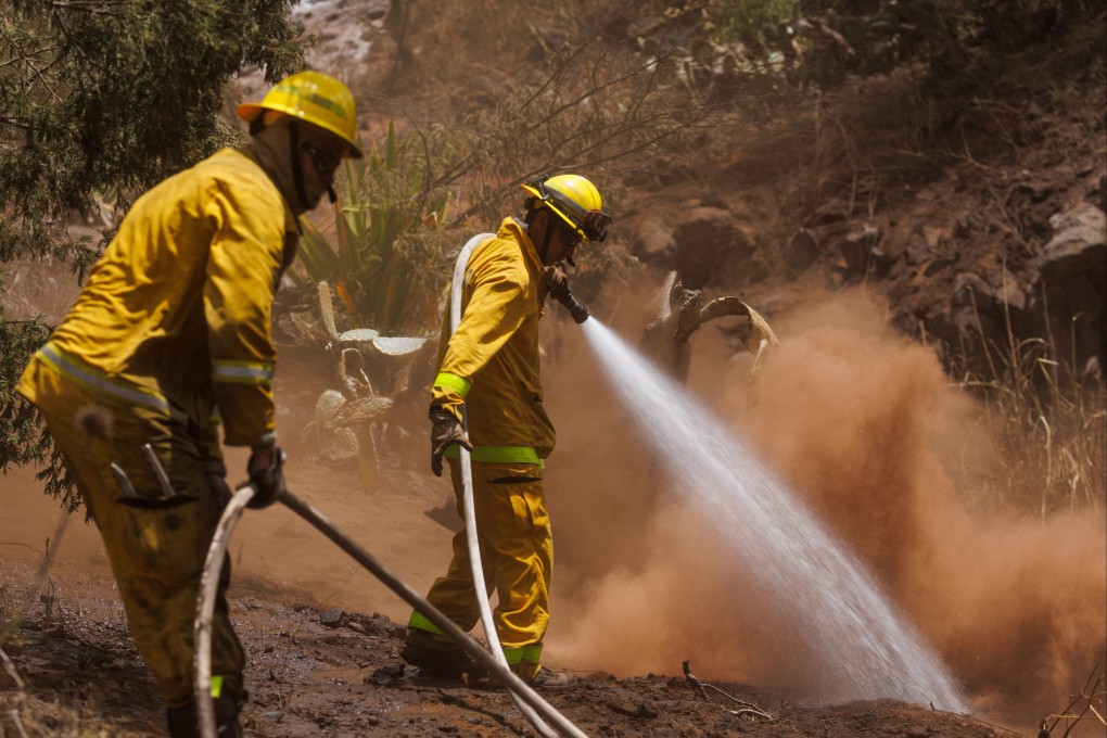 Maui County firefighters douse flare-up fires in a canyon in Kula on Maui, Hawaii, US on Monday. Photo: Reuters