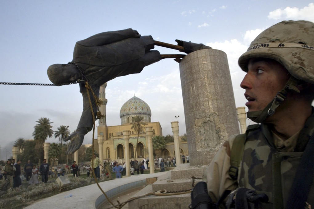 U.S. Marine Corp assaultman Kirk Dalrymple watches as a statue of Iraq’s president Saddam Hussein falls in central Baghdad on April 9, 2003. Photo: Reuters