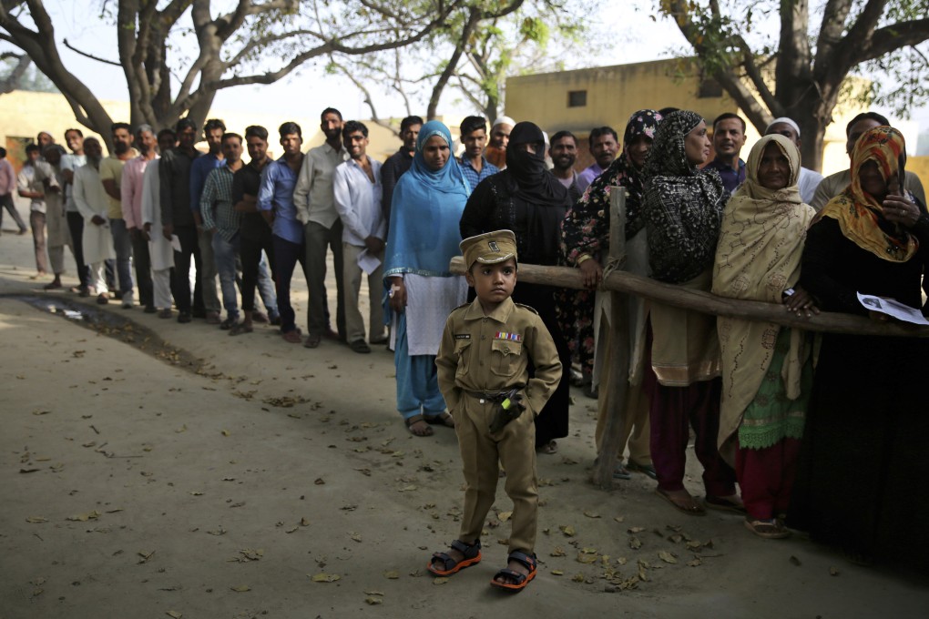 A boy dressed as a policeman stands as people queue to cast their votes in a village near Meerut, Uttar Pradesh, India, in 2019. Photo: AP