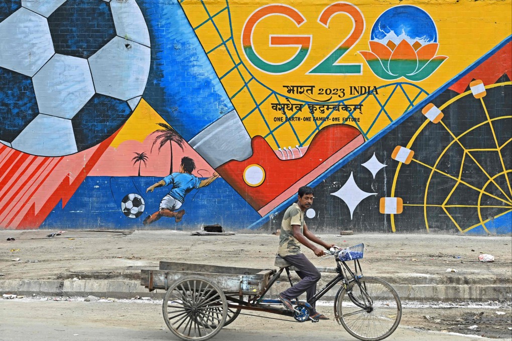 A man rides his cart past a wall mural with India’s G20 summit logo in New Delhi on Tuesday. Photo: AFP