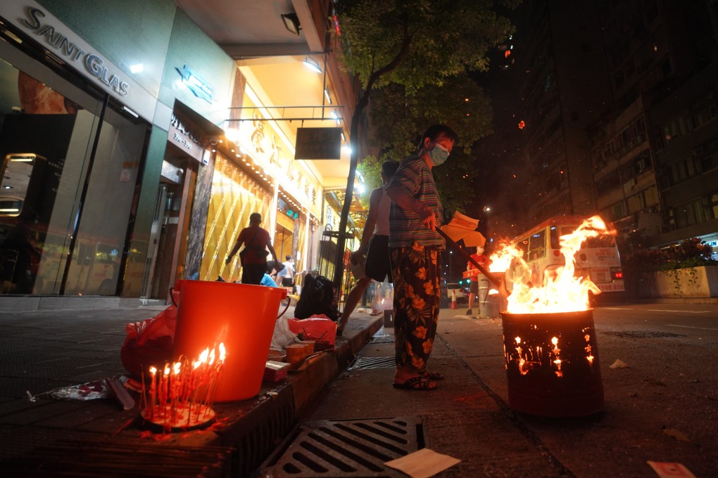 It is common in Chinese communities to see people, such as these men in Wan Chai, Hong Kong, burning paper offerings in the street during the Hungry Ghost Festival – to help wandering ghosts when they return to the afterlife. Photo: Winson Wong