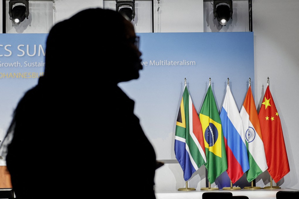 A woman stands near the flags of South Africa, Brazil, Russia, India and China during the 2023 BRICS Summit at the Sandton Convention Centre in Johannesburg on August 24, 2023. Photo: AFP