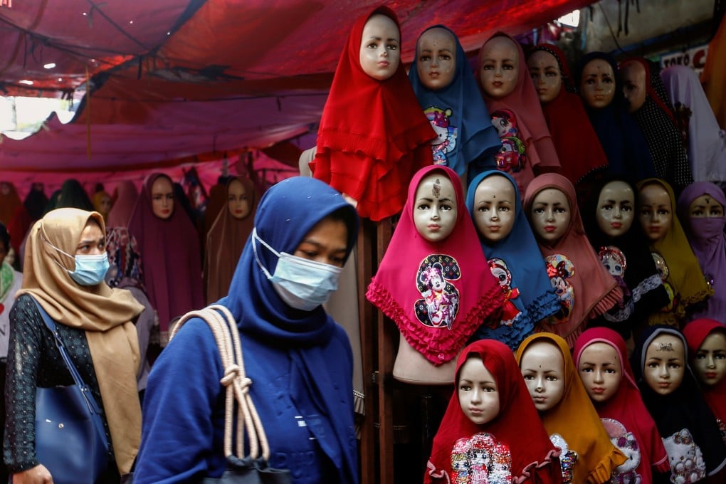 Women walk past hijabs displayed for sale at the Tanah Abang textile market in Jakarta, Indonesia. Photo: Reuters