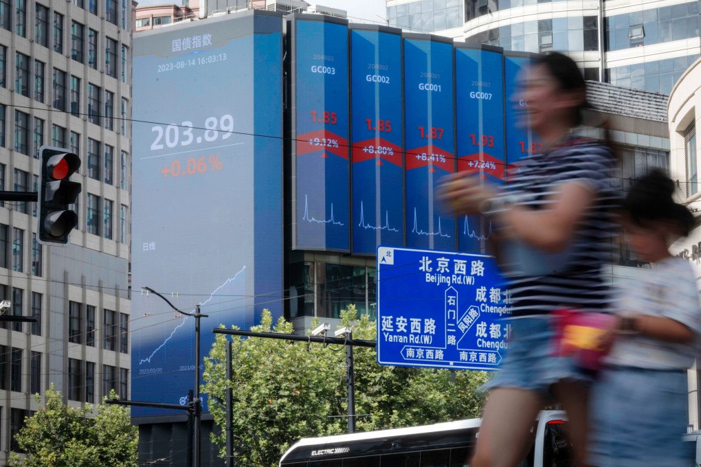 People walk on the street in front of a large screen showing latest stock exchange data, in Shanghai on August 14. Photo: EPA-EFE
