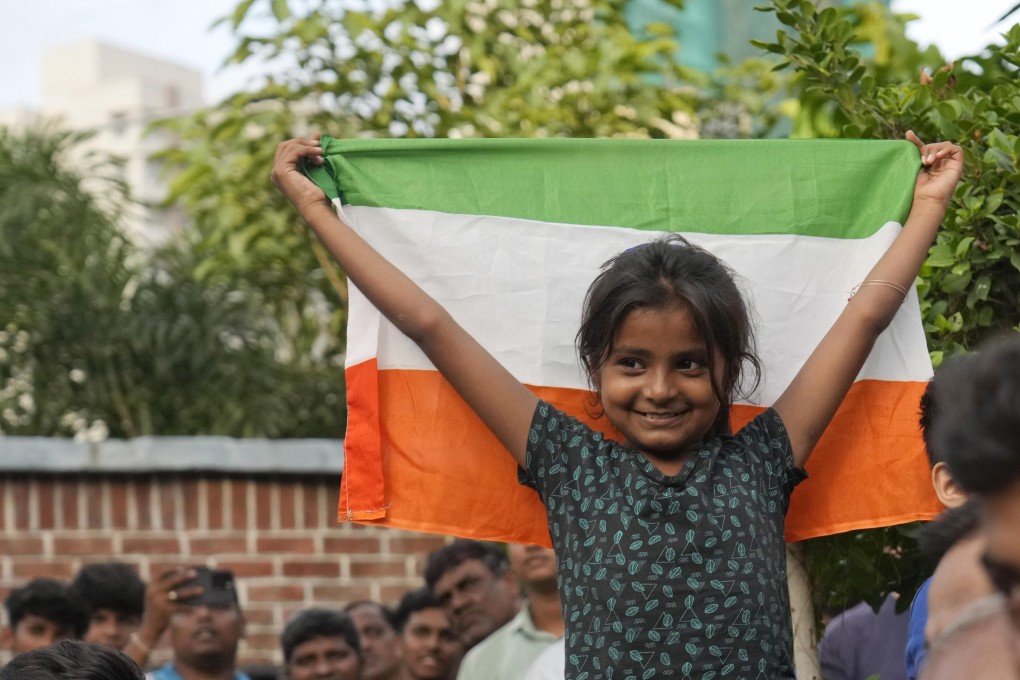 A girl holds aloft the Indian national flag as she watches a live telecast of the moon landing of Chandrayaan-3, in Mumbai, on August 23. Photo: AP