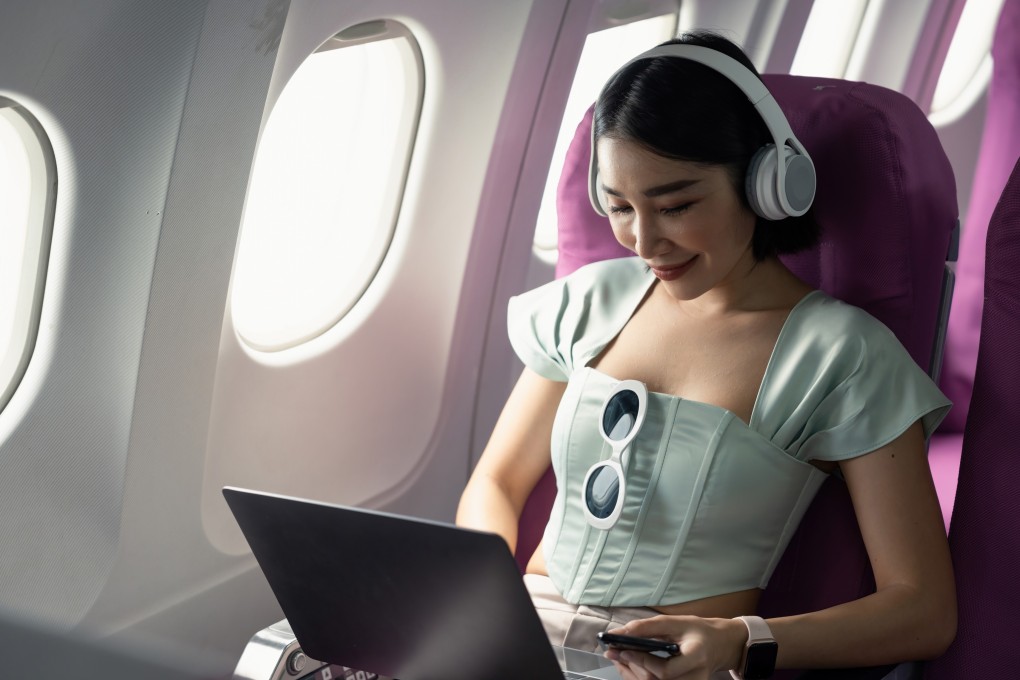A passenger Plane passenger uses her computer while wearing headphones. Corendon Airlines is launching child-free zones on its flights. Photo: Shutterstock