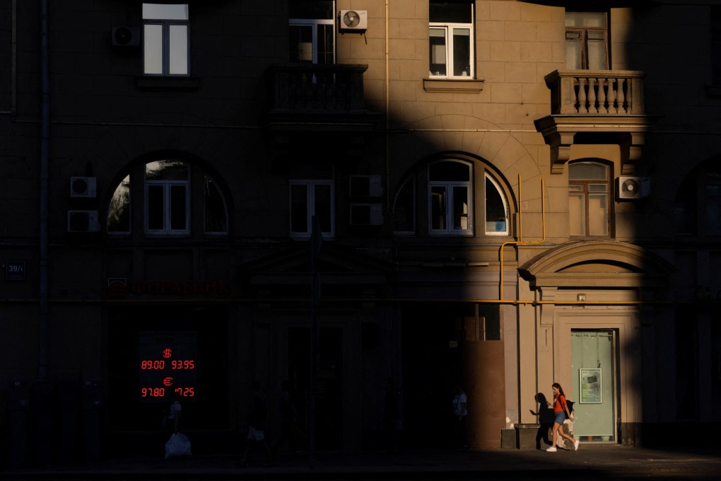 People walk next to a board showing currency exchange rates of the US dollar and euro against Russian rouble in a street in Moscow, Russia, on August 17. Photo: Reuters