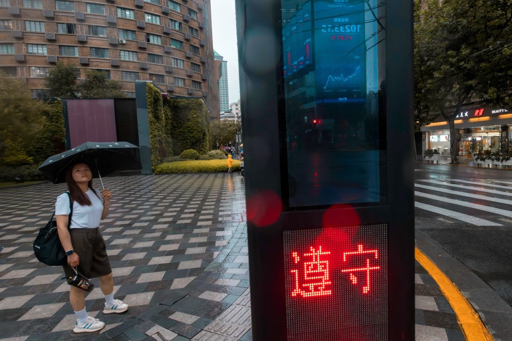 A screen displaying the latest stock exchange data is reflected in a traffic light post, in Shanghai, on August 28. Investors must take the probabilities of what they think the mainland economic authorities will do and decide to buy now or hold off. Photo: EPA-EFE