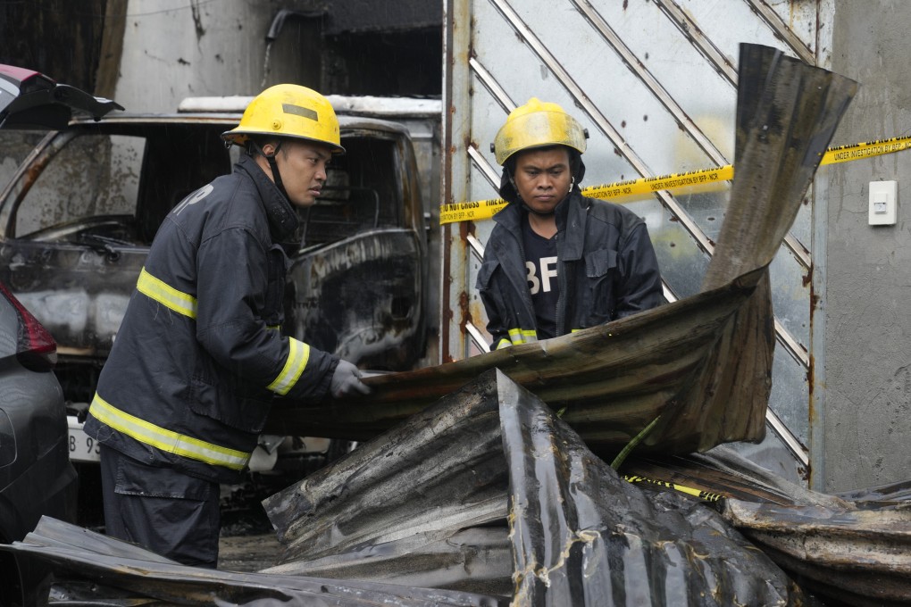Firemen arrange steel sheets from a factory that caught fire in Quezon city, Philippines on Thursday. Photo: AP