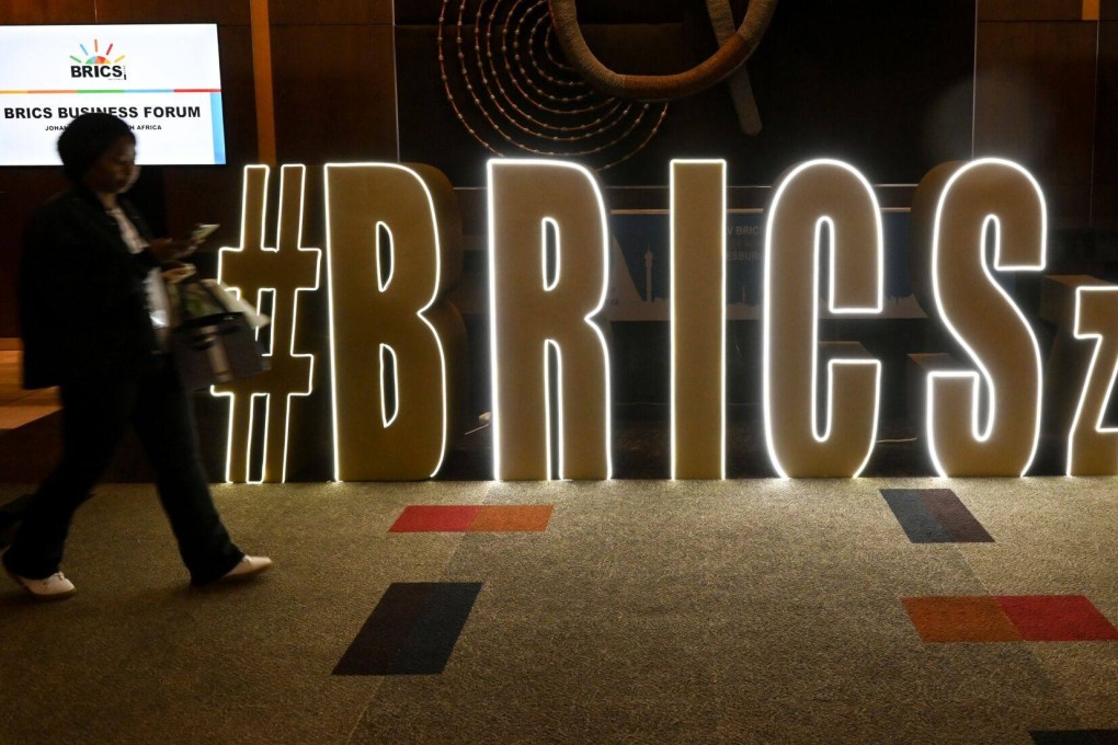 A visitor passes an illuminated sign during the Brics summit at the Sandton Convention Center in Johannesburg, South Africa, on August 22. In addition to expanding its membership, a primary focus of the grouping has been developing alternatives to using the US dollar and increasing the use of local currencies in trade and investment. Photo: Bloomberg