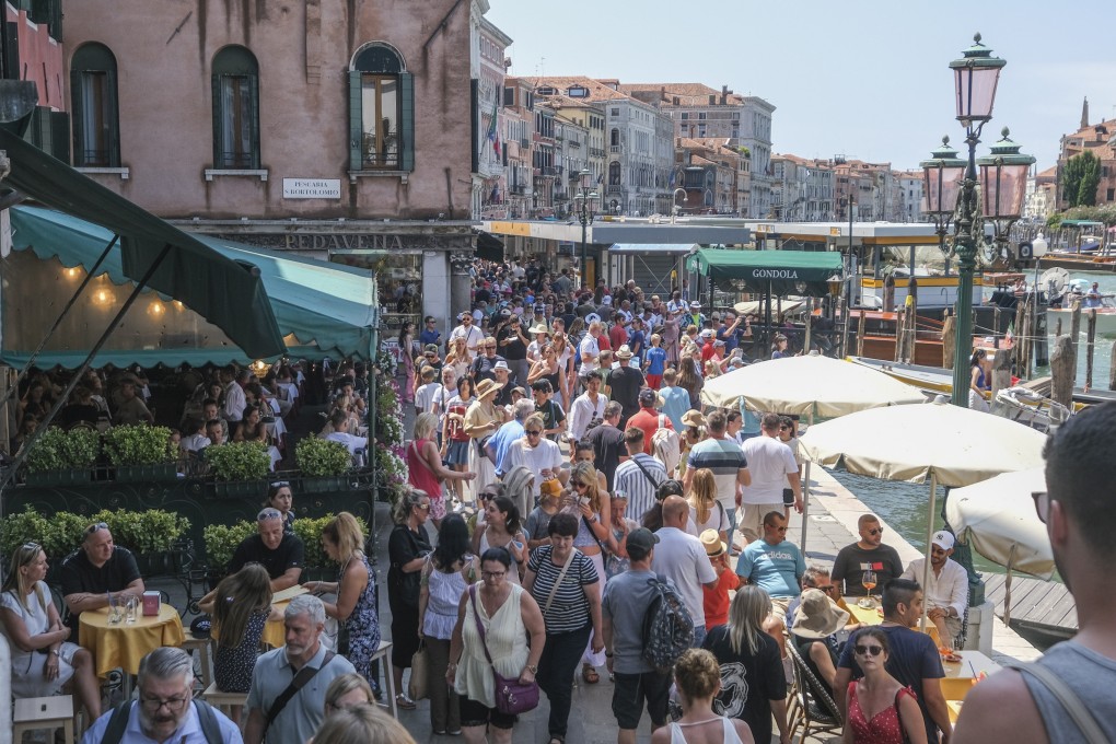 Tourists crowd the area near the Rialto Bridge in Venice on a day in August 2023. The city council has approved guidelines for trials of a new entry fee in 2024 for day trippers visiting the city. Photo: Getty Images