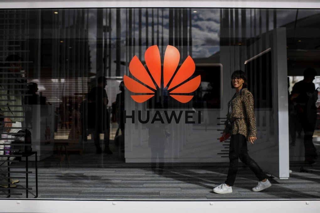 A woman walks past the logo of Huawei in Lisbon. Photo: AFP