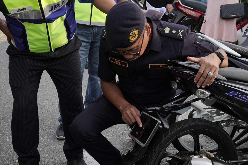 The motorcycle licence plate discovered by Malaysian police was smaller than one of the officer’s fingernails, and its numbers could barely be seen. Photo: Facebook/Jabatan Pengangkutan Jalan Malaysia